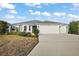 Inviting home with a large driveway, manicured lawn, and three-car garage at 5449 Dray Dr, The Villages, FL 32163