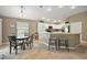Bright eat-in kitchen featuring white cabinetry, stainless steel appliances, breakfast bar with seating, and wood-look flooring at 5449 Dray Dr, The Villages, FL 32163