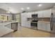 Bright kitchen featuring white cabinetry and stainless steel appliances, with a view of the living room at 5449 Dray Dr, The Villages, FL 32163