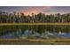 Scenic water view with mature trees and serene reflections under a colorful sky at 5449 Dray Dr, The Villages, FL 32163