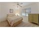 Cozy bedroom with a ceiling fan, window, and a decorative dresser and bed with matching linens at 1001 Del Rio Dr, The Villages, FL 32159