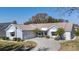 Charming light blue home featuring a circular paved driveway, well-manicured lawn, and mature landscaping at 1001 Del Rio Dr, The Villages, FL 32159