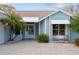 Close up of front of light blue house, shows front entry, paved driveway, and mature landscaping at 1001 Del Rio Dr, The Villages, FL 32159