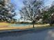 A tennis court surrounded by mature trees and grassy area on a sunny day at 10301 Us Highway 27 # 16, Clermont, FL 34711