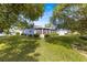 Expansive backyard view featuring a screened lanai, lush lawn, and mature landscaping at 10338 Se 178Th St, Summerfield, FL 34491