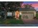 Beautiful exterior view of a home with an orange front door and warm lighting at 1067 Mesa Verde Court, Clermont, FL 34711