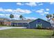 Charming blue home featuring a well-manicured lawn, a patterned driveway and landscaping with palm trees at 1102 N Palmetto St, Leesburg, FL 34748