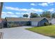 An angled view of a charming blue home with a patterned driveway and landscaping and a two car garage at 1102 N Palmetto St, Leesburg, FL 34748