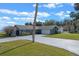 Exterior view of a well-maintained home with a spacious driveway, lush lawn, and mature trees at 1102 N Palmetto St, Leesburg, FL 34748