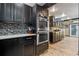 Modern kitchen with stainless steel double ovens, black cabinetry, mosaic backsplash, and wood floors at 1102 N Palmetto St, Leesburg, FL 34748