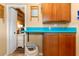 Functional laundry area with wood cabinets and blue counter, adjacent to another room at 1102 N Palmetto St, Leesburg, FL 34748