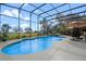 Screened pool with blue water and lounge area overlooking lush green space and lake in the distance at 1102 N Palmetto St, Leesburg, FL 34748