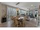 Open-concept dining room with wood floors and a long wooden table illuminated by pendant lighting, with access to the living room at 123 Bayou Bend Rd, Groveland, FL 34736