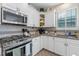 A charming kitchen featuring granite countertops, stainless steel appliances, and white cabinets with a decorative tile backsplash at 123 Bayou Bend Rd, Groveland, FL 34736