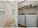 Organized laundry room with washer, dryer, storage shelves, and tiled floor at 123 Bayou Bend Rd, Groveland, FL 34736