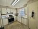 Cozy kitchen with white cabinetry, stainless steel appliances, tile flooring, and plenty of natural light from the window at 133 Hibiscus Way, Leesburg, FL 34748