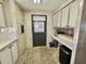 Eat in kitchen with tiled floor, wooden walls, white cabinets, and a black door leading to the exterior of the home at 133 Hibiscus Way, Leesburg, FL 34748