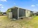 Rear view of the house with the screened porch and lush green grass at 1417 E Schwartz Blvd, The Villages, FL 32159