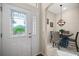 Inviting foyer with decorative glass front door leading to dining area with elegant chandelier and tile flooring at 1607 Quaker Ct, The Villages, FL 32163