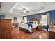 This spacious main bedroom features a tray ceiling, ceiling fan, and beautiful blue accent wall at 1607 Quaker Ct, The Villages, FL 32163