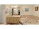 Bright bathroom features a corner tub, a vanity with a sink, and neutral tile at 1739 Lake Villa Dr, Tavares, FL 32778