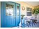 Charming front porch showcasing a vibrant blue door with decorative glass, framed by cozy seating and elegant decor at 1739 Lake Villa Dr, Tavares, FL 32778