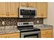 Close-up of a kitchen with stainless steel appliances, granite countertops, and wooden cabinets at 1739 Lake Villa Dr, Tavares, FL 32778