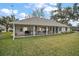 Covered patio overlooks a well-maintained backyard with mature trees and lush green grass at 19215 Park Place Blvd, Eustis, FL 32736