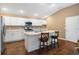 Kitchen showcases white cabinetry, stainless appliances, dark floors, and barstool seating at the island at 1930 Rhett Rd, The Villages, FL 32163