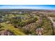 Scenic aerial view of community homes nestled among lush trees with a distant lake view and golf course at 202 Camino Real Blvd # 202, Howey In The Hills, FL 34737