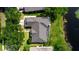 Aerial view of a home with a dark roof, lush yard, and nearby pond at 2041 Park Forest Blvd, Mount Dora, FL 32757