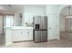 Open-concept kitchen with a stainless steel refrigerator and white cabinetry, seamlessly connecting to dining spaces at 2041 Park Forest Blvd, Mount Dora, FL 32757