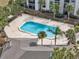 An aerial view of a sparkling blue pool with ample lounging space surrounded by lush tropical palm trees at 2130 Cascades Blvd # 101, Kissimmee, FL 34741