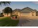 Beautiful home with a three car garage, beautiful landscaping, and a paver driveway at dusk at 2190 Derringer Ave, The Villages, FL 32162