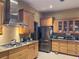 Well-lit kitchen featuring stainless steel appliances, wooden cabinets, tile backsplash, and granite countertops at 22244 County Road 455, Howey In The Hills, FL 34737