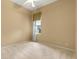 This bedroom features neutral carpet, paint and ceiling fan with an exterior view through the window at 27710 Snow Orchid Ct, Leesburg, FL 34748