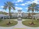 Elegant community center featuring a clock tower, palm trees, well manicured lawn, and inviting entrance at 27710 Snow Orchid Ct, Leesburg, FL 34748