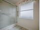 Bathroom showcasing a tiled shower behind sliding glass doors and a window with privacy glass at 305 Ranchwood Dr, Leesburg, FL 34748