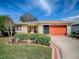 Charming single-story home with a well-manicured front yard and an orange garage door at 305 Ranchwood Dr, Leesburg, FL 34748