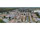 Aerial view shows a vibrant community with tree-lined streets, single-story homes, and nearby lake at 308 Emmalee Pl, The Villages, FL 32162