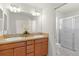 Bathroom featuring double sinks with wood cabinets and a shower with sliding glass doors at 3356 Blaise Ter, The Villages, FL 32163