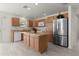 Kitchen with stainless steel refrigerator, light wood cabinets, and an island at 3356 Blaise Ter, The Villages, FL 32163