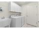 Well-lit laundry room with sink, washer, dryer and overhead cabinet storage at 3356 Blaise Ter, The Villages, FL 32163