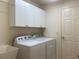 Bright laundry room with modern washer and dryer, upper cabinets, and utility sink at 3356 Blaise Ter, The Villages, FL 32163