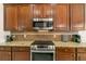 Close up of kitchen cook top, microwave, and granite countertops with tiled backsplash and dark wood cabinets at 3782 Avon Ct, Clermont, FL 34711