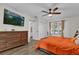 Cozy bedroom with an orange bedspread, wood dresser, ceiling fan, and bright windows at 3901 Woodglade Cv, Winter Park, FL 32792