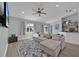 Inviting living room with a comfortable sectional sofa, ceiling fan and a view into kitchen at 406 Bramble Way, Minneola, FL 34715