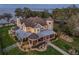 Aerial shot showing a grand yellow estate with a lake view, surrounded by lush landscaping and manicured gardens at 415 Carman Dr, Leesburg, FL 34748