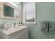 Bathroom with white vanity, decorative mirror, and serene light-blue painted walls at 415 Carman Dr, Leesburg, FL 34748