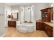 Elegant bathroom featuring a soaking tub, a dark wood cabinet and many windows at 415 Carman Dr, Leesburg, FL 34748